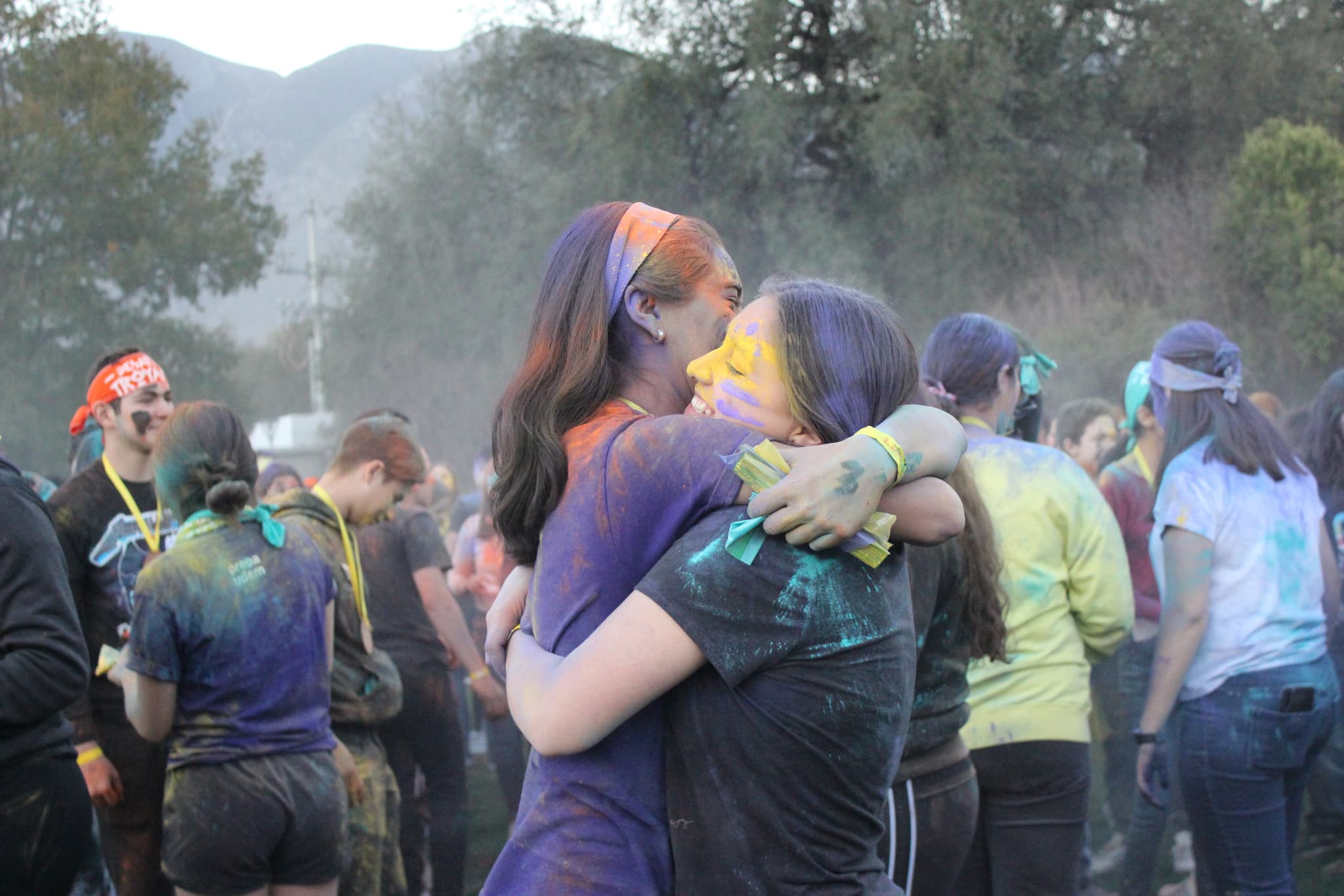 Dos niñas abrazándose después de una actividad con colores, destacando la conexión emocional creada en el campamento