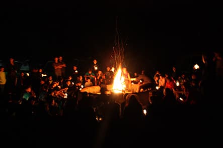 Campamento nocturno con niños alrededor de una fogata, creando vínculos y experiencias inolvidables.