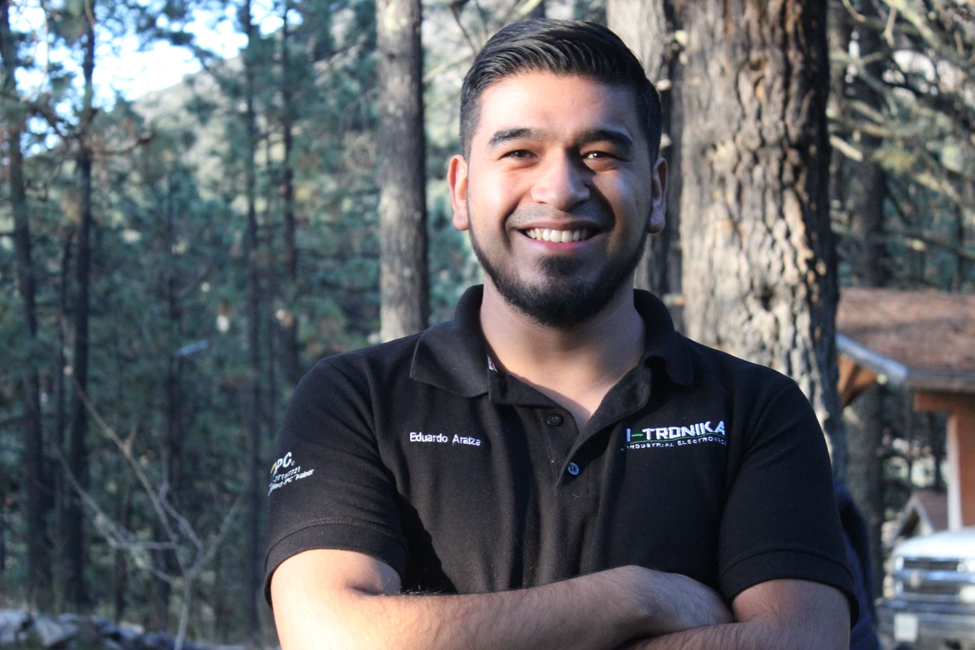 Hombre sonriente con camisa de ALYAX, mostrando confianza y profesionalismo durante una actividad grupal
