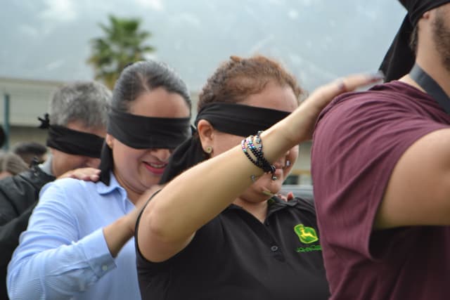 Ejercicio grupal donde los participantes trabajan con los ojos vendados, promoviendo confianza y coordinación en equipos de trabajo