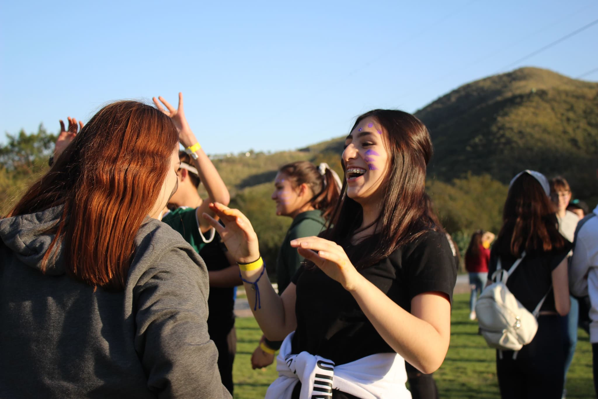Dos compañeras riendo juntas durante una actividad al aire libre, mostrando el impacto positivo de la integración