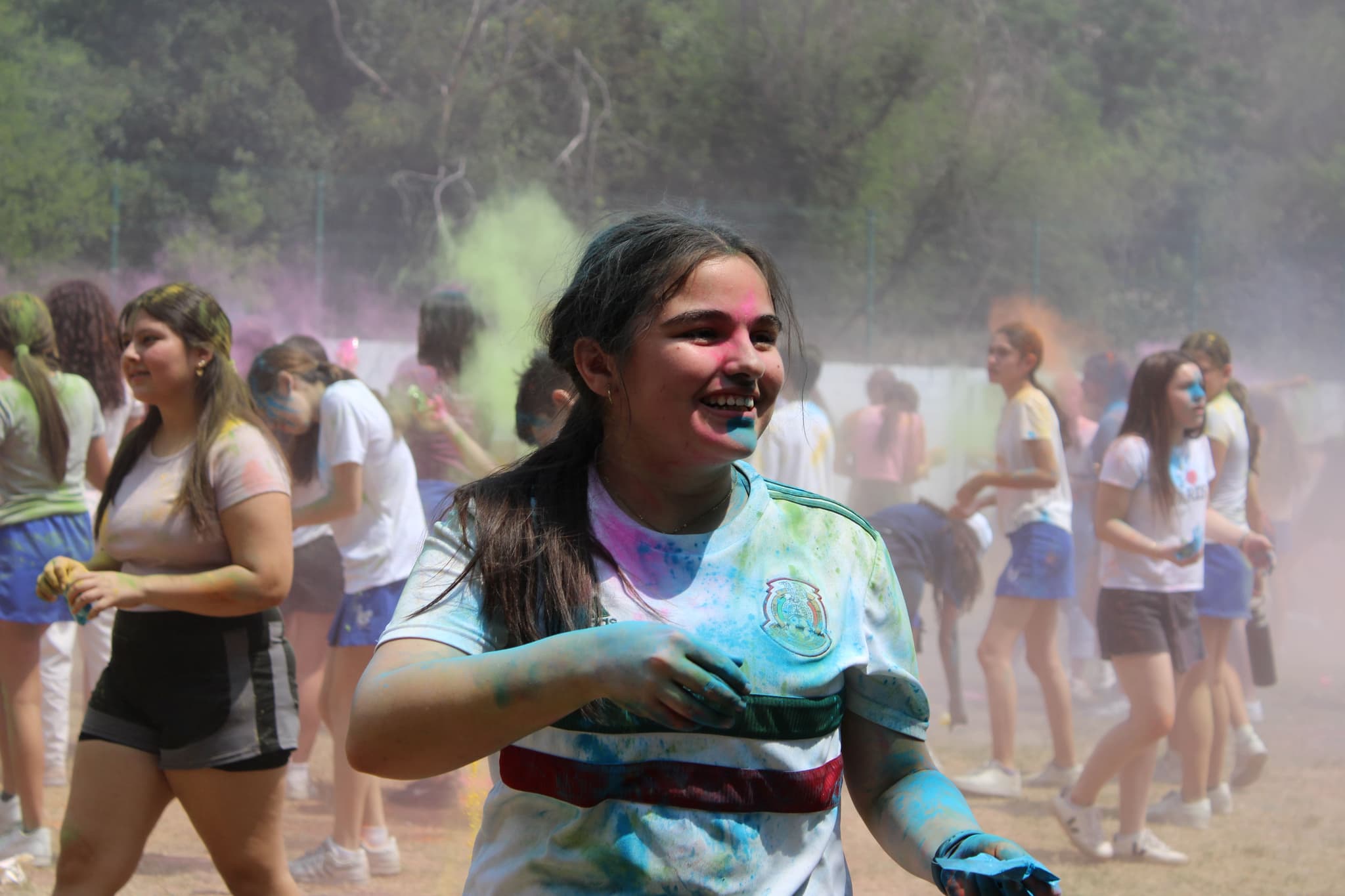 Alumna cubierta de colores durante una actividad festiva, simbolizando la unión y la alegría entre compañeros