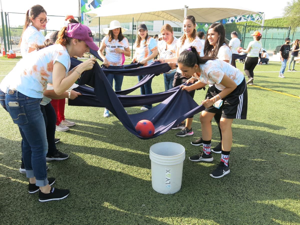 Docentes trabajando juntos para manejar una pelota con tela, mostrando coordinación y esfuerzo conjunto