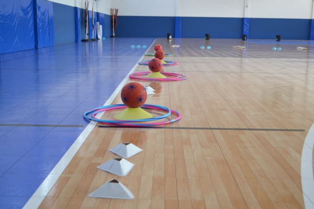 Vista de un reto en interiores con aros y pelotas, diseñado para fomentar la creatividad y la cooperación entre maestros