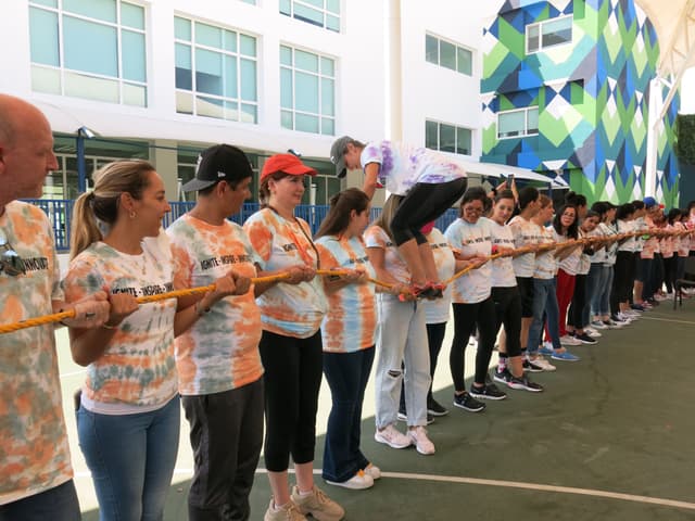 Maestros trabajando juntos en una dinámica al aire libre, superando retos físicos que promueven la confianza mutua