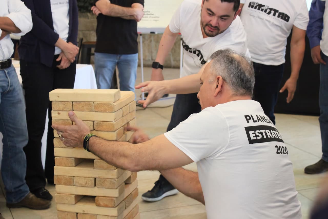 Participantes resolviendo un desafío con bloques de madera, demostrando habilidades de comunicación y organización grupal
