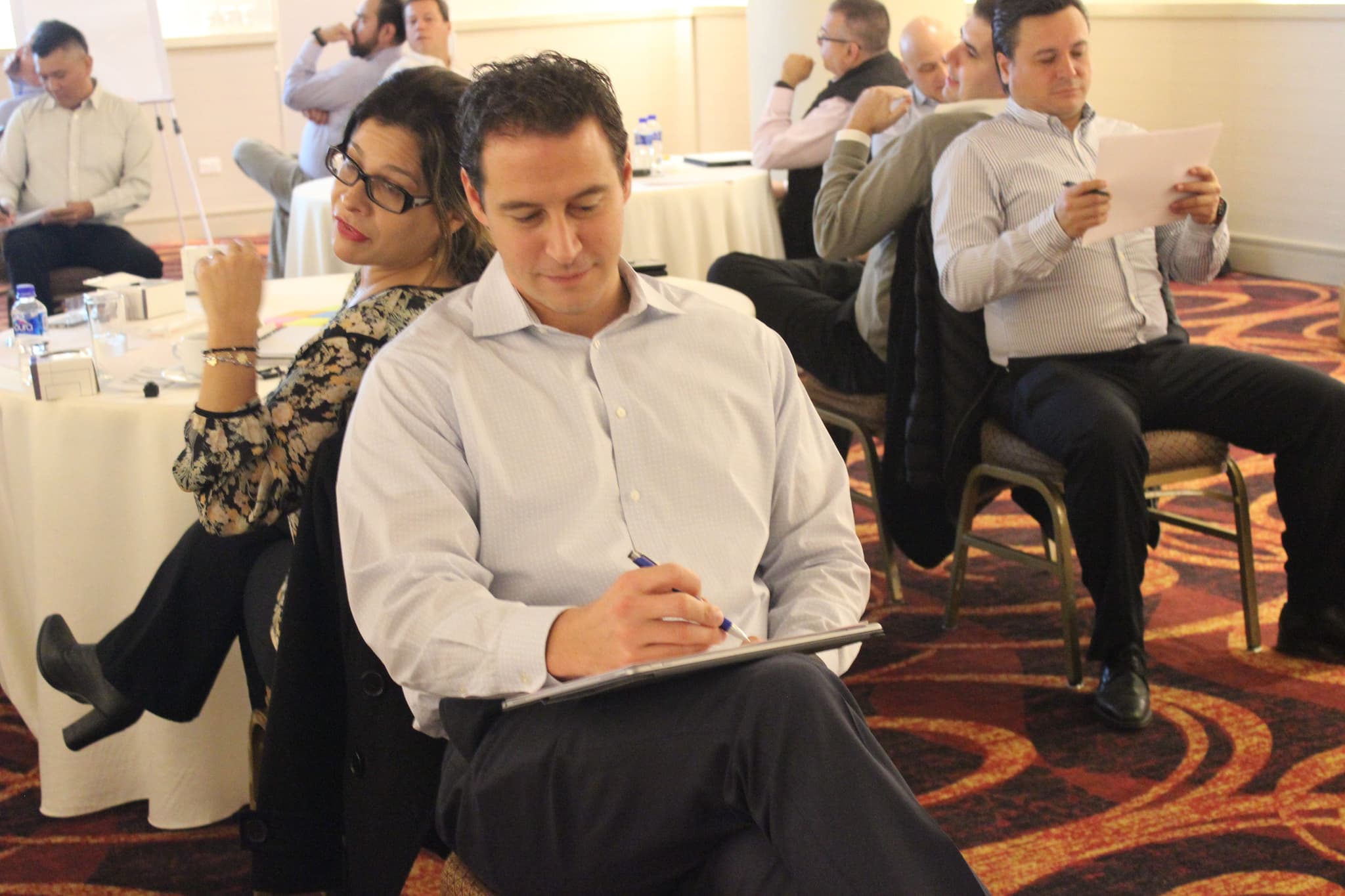 Colaborador tomando notas durante una sesión, destacando la importancia del aprendizaje práctico en las dinámicas de equipo